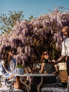 Wisteria in Stanwell House garden bar with two individuals drinking prosecco